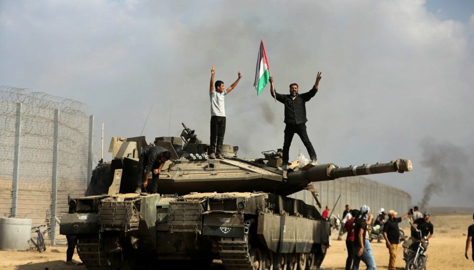 Palestinere vifter med et flagg oppå en ødelagt israelsk stridsvogn ved grensa mellom Israel og Gazastripen øst for Khan Younis lørdag. Palestinere vifter med det palestinske flagget på en ødelagt israelsk stridsvogn på Gazastripen, ved grensegjerdet øst for Khan Younis sør i enklaven lørdag. Foto: Yousef Masoud / AP / NTB
