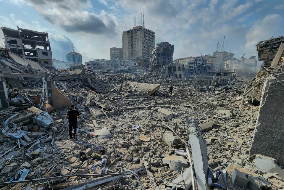 Palestinere i et område som ble bombet av Israel i Gaza by tirsdag. En palestinsk mann går gjennom ruinene av sammenraste bygninger i Gaza by tirsdag. Siden lørdag har minst 900 mennesker blitt drept i angrep mot Gazastripen. Foto: Hassan Eslaiah / AP / NTB