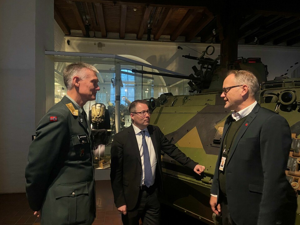 Fra venstre: Arne Opperud (sjef i Forsvarets fellestjenester), Bjørn Arild Gram (forsvarsminister), Erling Kjærnes (direktør for Forsvarets museer). Menn i dress står på Forsvarets museum.