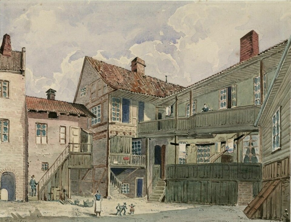 Barndommens lekeplass. Bildet viser en bakgård i Øvre Voldgate, der Emil bodde som barn, med unger som leker og voksne som følger med fra svalgangene. Barndommens lekeplass. Bildet viser en bakgård i Øvre Voldgate, der Emil bodde som barn, med unger som leker og voksne som følger med fra svalgangene.
