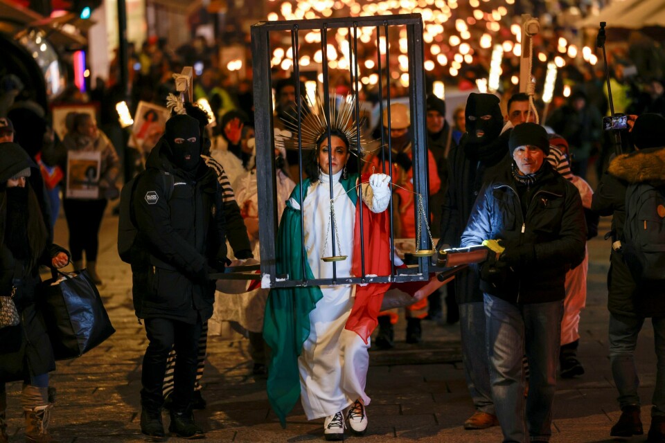 Kvinnen bak gitteret leder an Nobel-fakkeltoget nedover Karl Johans gate. Kvinnen bak gitteret leder an Nobel-fakkeltoget nedover Karl Johans gate. Foto: Hanna Johre / NTB