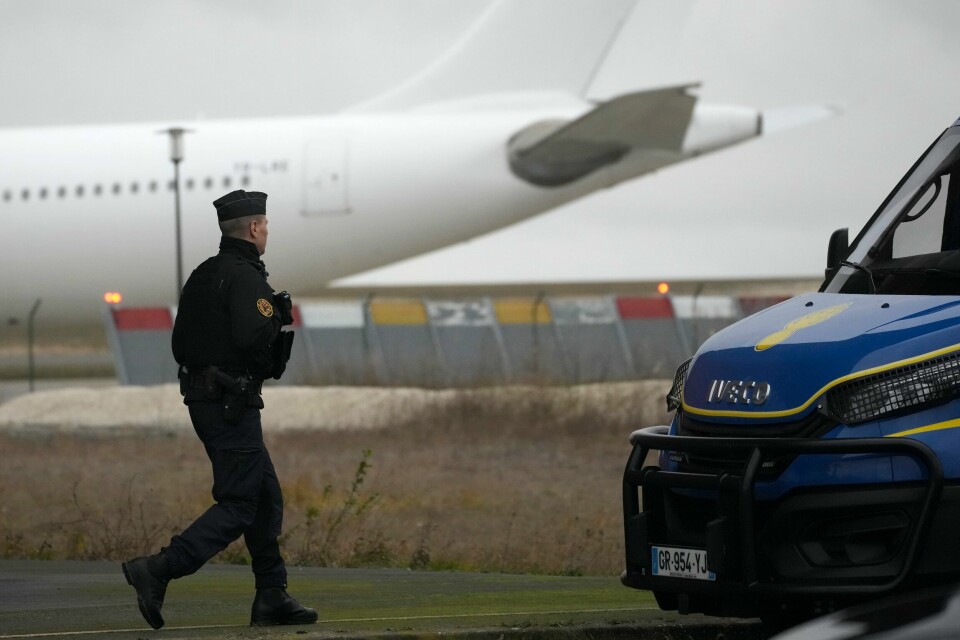 En politibetjent holder vakt ved flyplassen i Vatry i Frankrike der et fly med over 300 indiske borgere har blitt holdt tilbake siden torsdag grunnet mistanke om menneskesmugling. En politimann går foran flyet som angivelig ble brukt i en stor menneskehandelsoperasjon. Foto: Christophe Ena / AP / NTB