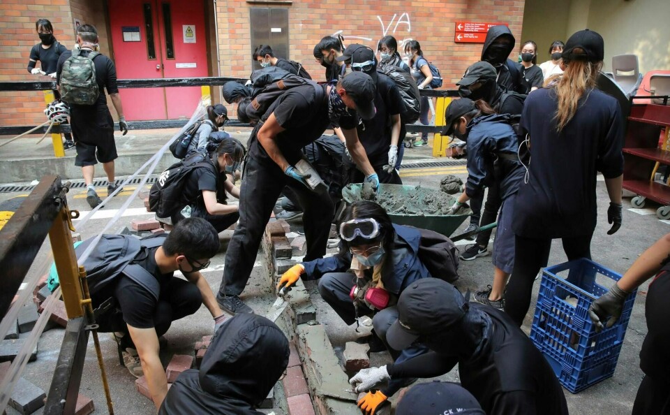 Demonstranter i Hongkong bygger en mur tvers over en vei i nærheten av universitetet NTNU-studentene studerer ved.