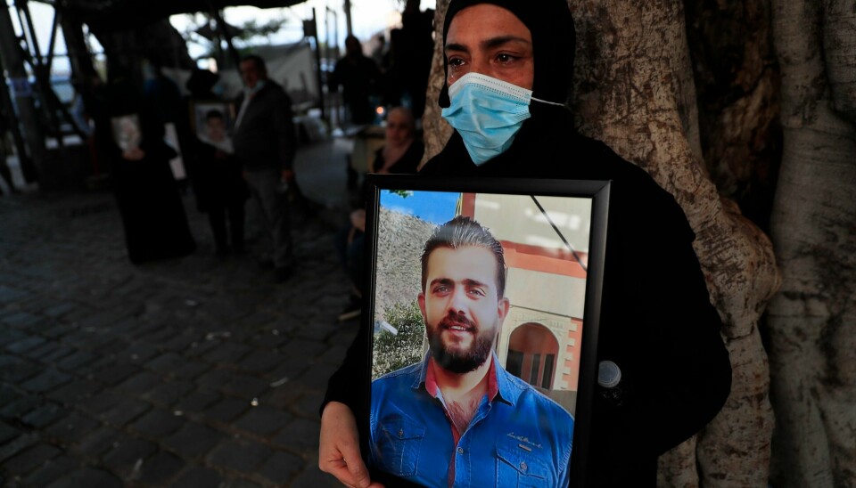 En kvinne holder et bilde av sin drepte sønn under en minneseremoni i Beirut fire måneder etter eksplosjonen som la store deler av byen i grus.