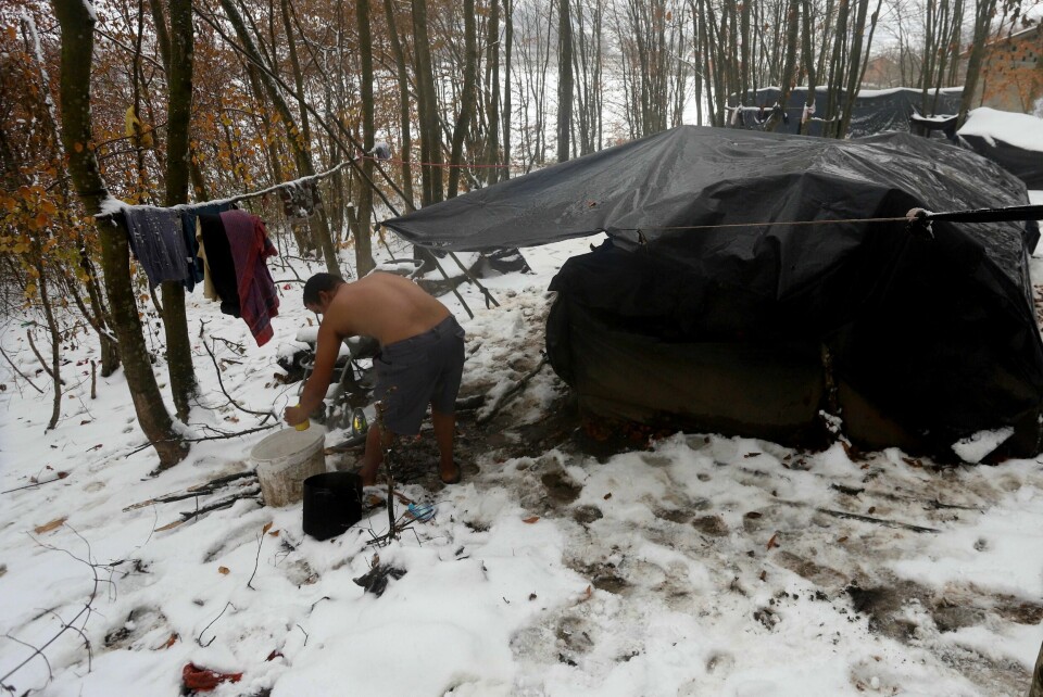 A migrant cleans himself up next to improvised tents at a makeshift camp in a forest outside Velika Kladusa, Bosnia, Thursday, Dec. 3. 2020. Their long journeys already filled with uncertainty and hardship, migrants stranded in Bosnia are now facing another adversity _ a cold Balkan winter. As this season's first snow fell this week in parts of the region, many migrants living in make-shift tent settlements in western Bosnia are struggling to stay dry and warm. (AP Photo/Joan Giralt)