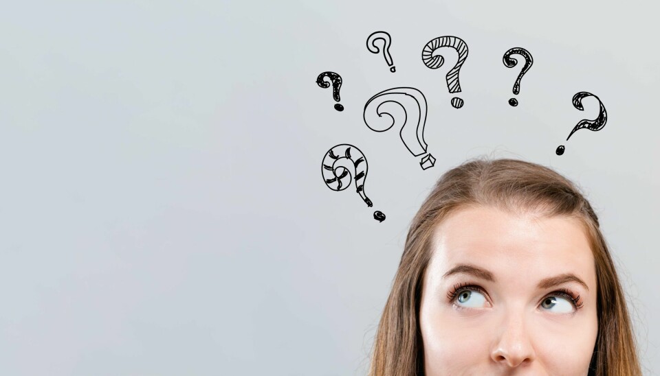 Hand draw question marks with young woman looking upwards on a gray background