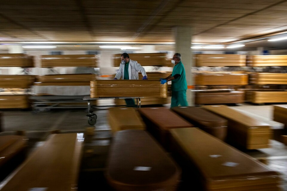 Arbeidere flytter en kiste med en person som har dødd av korona, mens andre kister blir lagret og venter på begravelse eller kremering ved Collserola-likhuset i Barcelona, Spania 2. april. Workers move a coffin with the body of a victim of COVID-19 as other coffins are stored waiting for burial or cremation at the Collserola morgue in Barcelona, Spain, on April 2, 2020. (AP Photo/Emilio Morenatti)