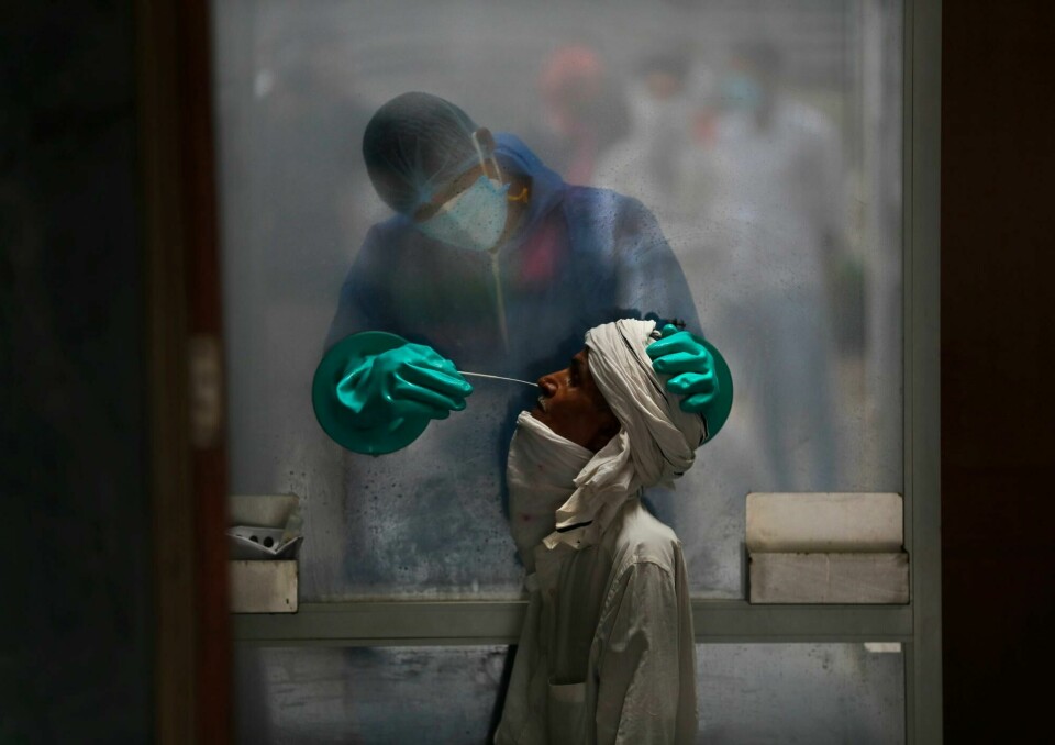 En helsearbeider tar en koronatest på et sykehus i New Delhi, India. A health worker takes a nasal swab of a person for a COVID-19 test at a hospital in New Delhi, India, on July 6, 2020. (AP Photo/Manish Swarup)