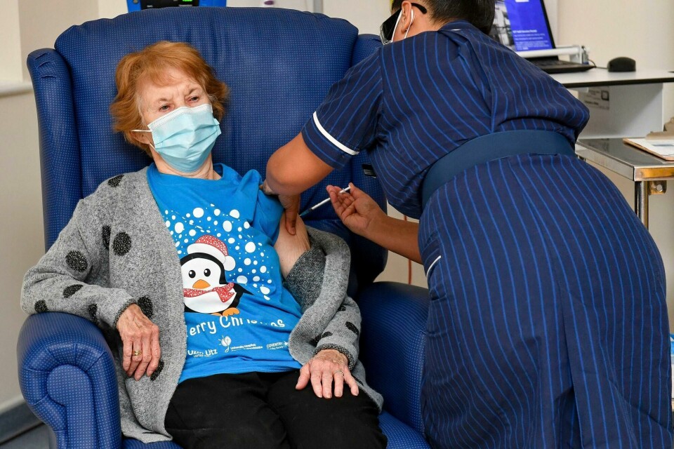 90 år gamle Margaret Keenan blir den første i Storbritannia som får vaksine mot covid-19. FILE - In this Tuesday, Dec. 8, 2020 file photo, 90 year old Margaret Keenan, the first patient in the UK to receive the Pfizer-BioNTech COVID-19 vaccine, administered by nurse May Parsons at University Hospital, Coventry, England. As Canadians, Britons and Americans begin getting immunized with a German-developed vaccine against the coronavirus, pressure is building on the European Medicines Agency to approve the shot made by Pfizer Inc. and German company BioNTech. Those countries all approved the COVID-19 vaccine under emergency use rules, meaning it is an unlicensed product. But the EMA approval process for coronavirus vaccines is largely similar to the standard licensing procedure that would be granted to any new vaccine, only on an accelerated schedule. (Jacob King/Pool via AP, File)