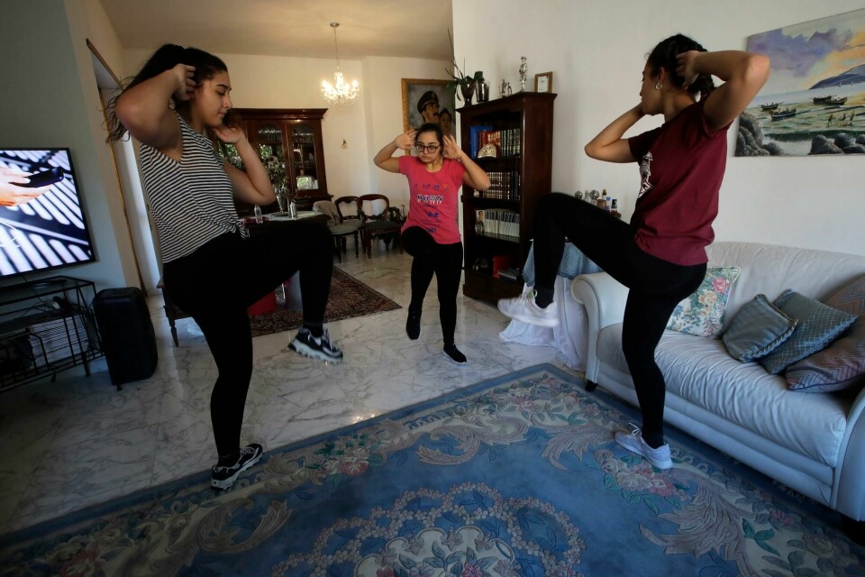 Selene Mirra (i midten) trener med søstrene sine Aurora (t.v.) og Sabrina i familiens stue i Roma. Selene driver egentlig med synkronsvømming og er på Italias landslag for personer med downs syndrom. Selene Mirra, center, trains with her sisters, Aurora, left, and Sabrina in the living room of their home in Rome on April 4, 2020. Selene, an athlete on the Italian Down syndrome synchronized swimming team, continues her training despite the Tokyo 2020 postponement due to COVID-19. (AP Photo/Alessandra Tarantino)