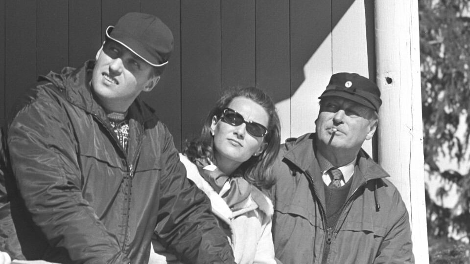 Sonja Haraldsen avbildet sammen med sin forlovede kronprins Harald og en, for anledningen, sigarettdampende kommende svigerfar kong Olav i Skuibakken under NM i hopp 31. mars 1968. Harald og Sonja giftet seg fem måneder senere. Foto: NTB scanpix