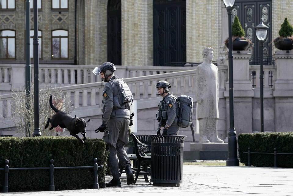 Væpnet politi utenfor Stortinget der alle innganger ble stengt onsdag formiddag på grunn av bombetrusler. PST skal nå starte etterforskning. Politi med hund undersøker området utenfor Stortinget etter at det ble fremsatt to trusler mot Stortinget. Foto: Cornelius Poppe / NTB