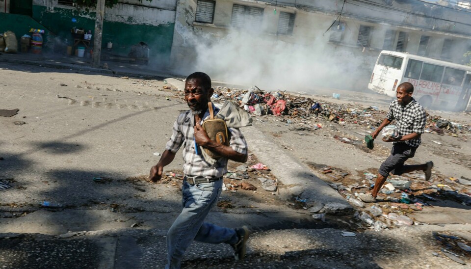 To menn løper i dekning mens opprørspolitiet skyter tåregass i et forsøk på å spre folk i nærheten av presidentpalasset i Port-au-Prince tirsdag denne uken. To menn løper i dekning mens opprørspolitiet skyter tåregass i et forsøk på å spre folk i nærheten av presidentpalasset i Port-au-Prince tirsdag denne uken. Foto: Odelyn Joseph / AP / NTB