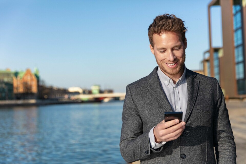 Å svare på betalte nettundersøkelser er en lettvint måte for å tjene litt ekstra penger ved siden av jobb og studier. Mann ser på telefonen sin.