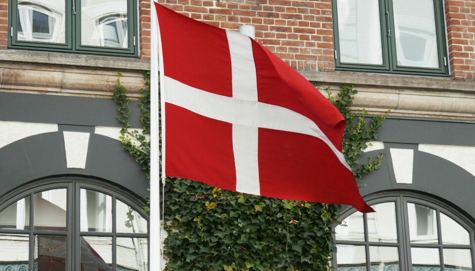 Det danske flagget Dannebrog vaier i vinden i hovedstaden København. Danmark reduserer kapasiteten for koronatesting. Foto: Erik Johansen / NTB