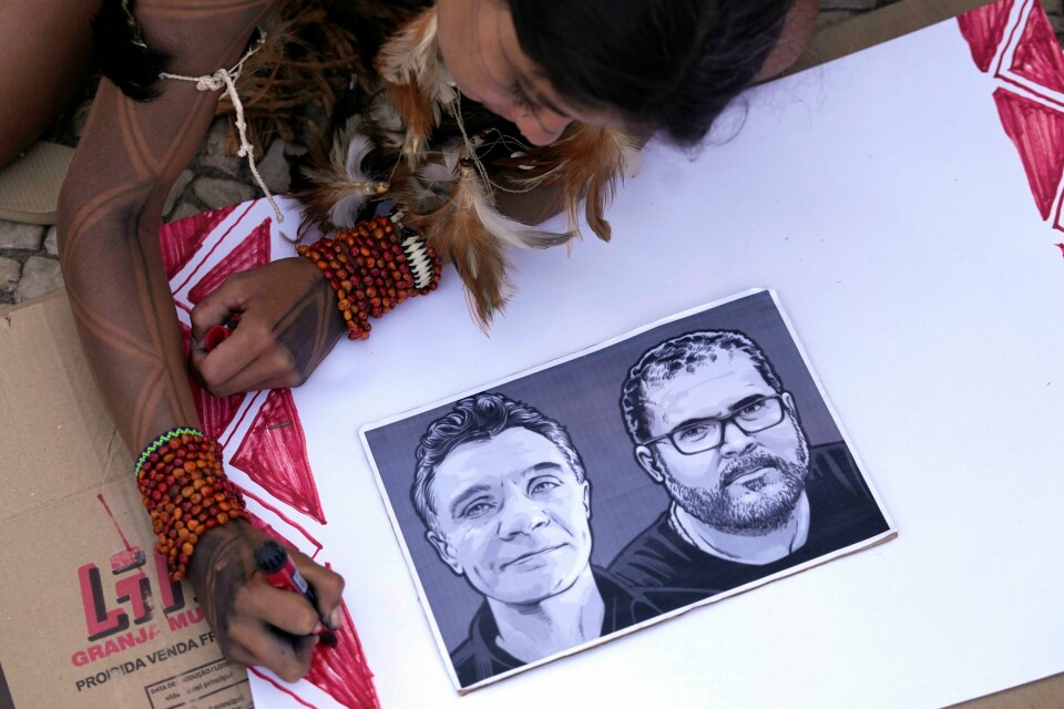 En jente fra den brasilianske urbefolkningen farger en plakat med et bilde av den drepte britiske journalisten Dom Phillips og urfolkseksperten Bruno Pereira. En jente fra den brasilianske urbefolkningen farger en plakat med et bilde av den drepte britiske journalisten Dom Phillips og urfolkseksperten Bruno Pereira. Foto: Eraldo Peres / AP / NTB