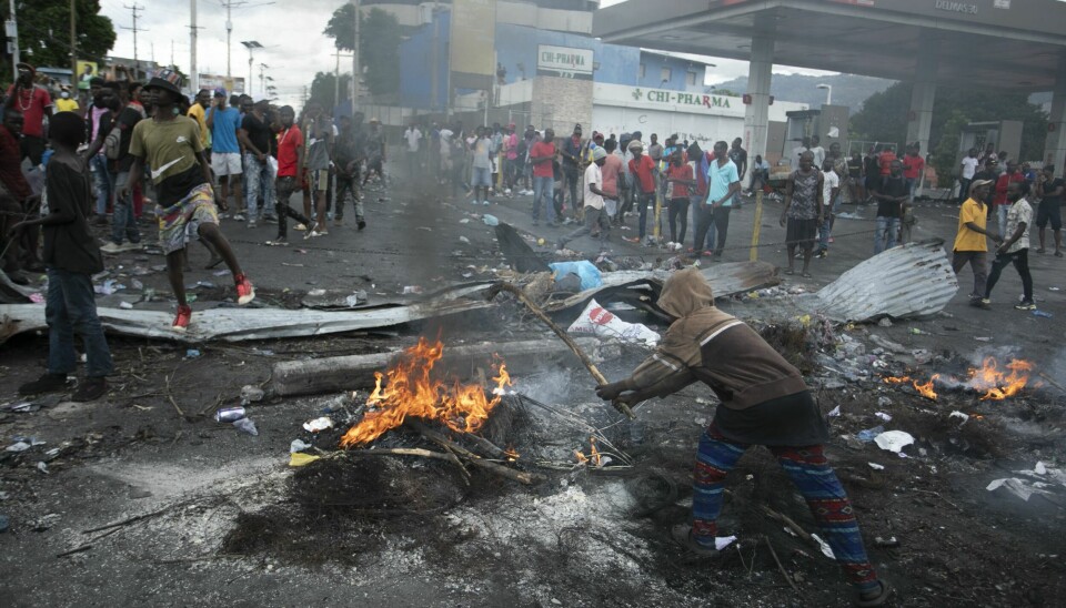 Demonstranter samler seg rundt en barrikade som er satt opp i protest mot økte drivstoffpriser. FNs Haiti-utsending sier at det utspiller seg en humanitær katastrofe i landet etter to uker med voldelige opptøyer. Demonstranter samler seg rundt en barrikade som er satt opp i protest mot økte drivstoffpriser. FNs Haiti-utsending sier at det utspiller seg en humanitær katastrofe i landet etter to uker med voldelige opptøyer. Foto: Odelyn Joseph / AP / NTB