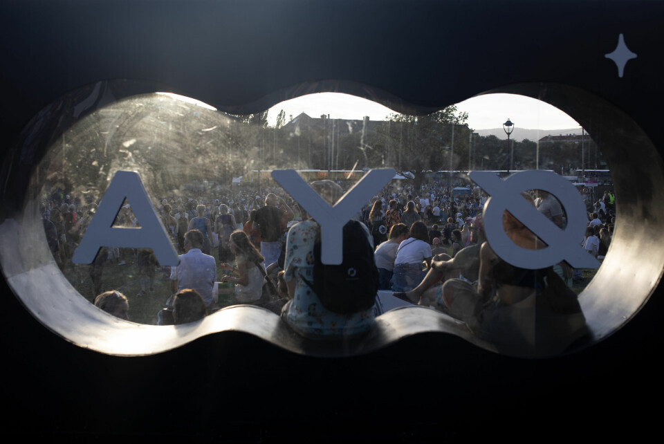 På innsiden av Øyalogoen tar et par festivaldeltakere en velfjortjent pause, mens festivalen rusler forbi utenfor. Øya