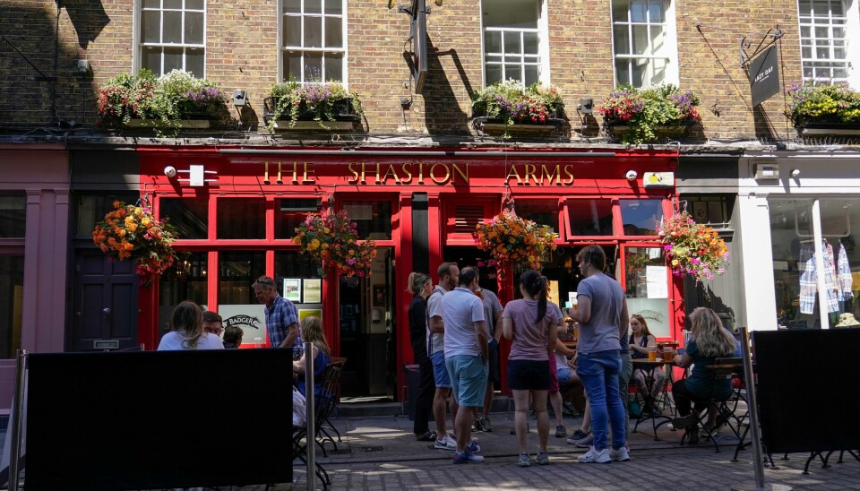 Under sommerens hetebølge valgte mange å stå i skyggen med noe kaldt i glasset på denne puben i Soho. En rekke serveringssteder har ikke overlevd pandemien, og verst er det litt lenger øst i London, der mangel på både pendlere og turister har ført til at hver sjuende pub, bar og restaurant har stengt dørene for godt. Illustrasjonsfoto. Under sommerens hetebølge valgte mange å stå i skyggen med noe kaldt i glasset på denne puben i Soho. En rekke serveringssteder har ikke overlevd pandemien, og verst er det litt lenger øst i London, der mangel på både pendlere og turister har ført til at hver sjuende pub, bar og restaurant har stent dørene for godt. Illustrasjonsfoto: Alberto Pezzali / AP / NTB