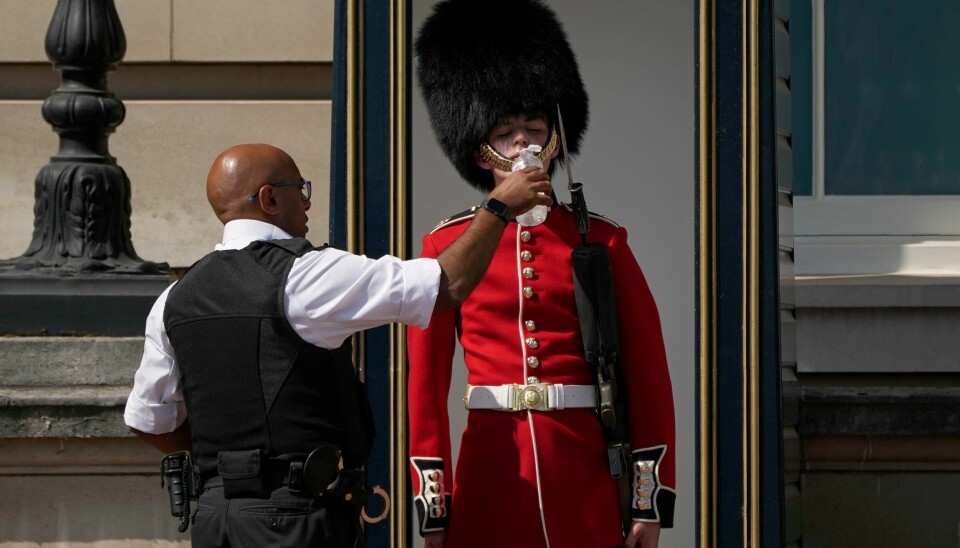 En av vaktene utenfor Buckingham Palace i London fikk vann av en politimann da det ble satt temperaturrekorder i Storbritannia i juli. En av vaktene utenfor Buckingham Palace i London fikk vann av en politimann da det ble satt temperaturrekorder i Storbritannia i juli.