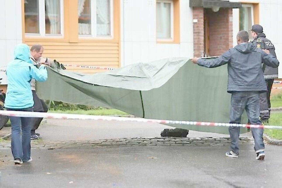 Politietterforskere dekker til skolesekken som ligger igjen på bakken utenfor blokka på Kalbakken i Oslo etter at en kvinne i 40-årene ble knivstukket og drept av sin fraseparerte ektemann 28. august i år. Også sønnen ble knivstukket. FOTO: HÅKON MOSVOLD LARSEN/NTB SCANPIX