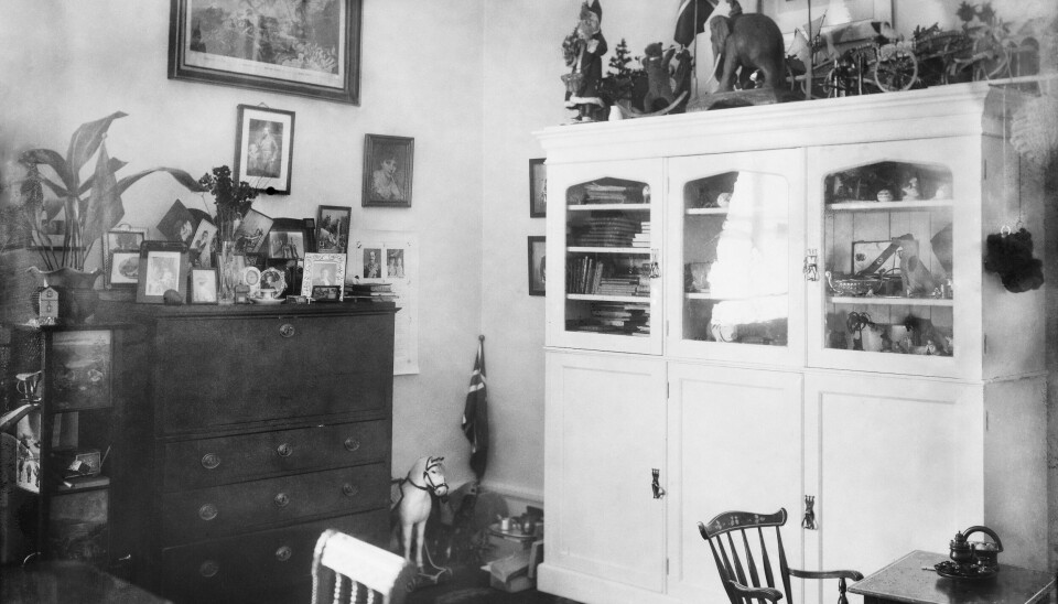 Prins Olavs lekeværelse på slottet i 1909. Et innredet barnerom med skap med dører, en kommode med mange barneleker og bilder på veggene