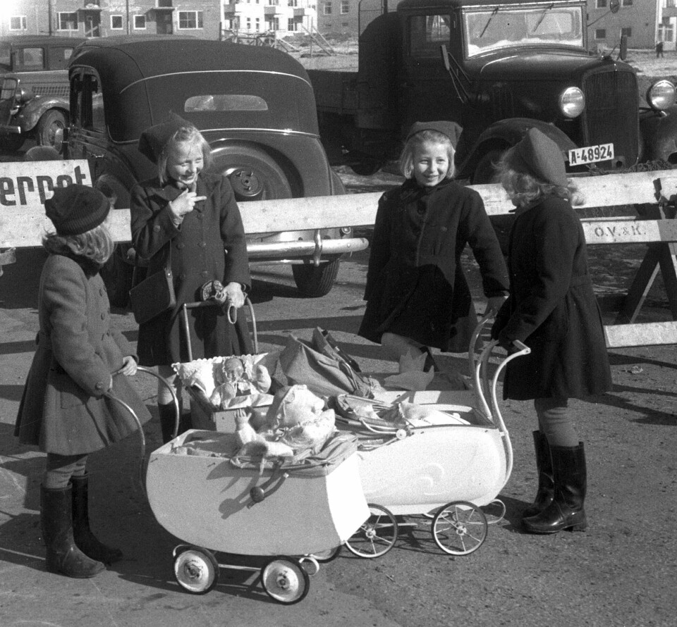 Jenter med dokker og dokkevogner, mars 1948. Fire jenter med dokker og dokkevogner, mars 1948. Biler i bakgrunnen.