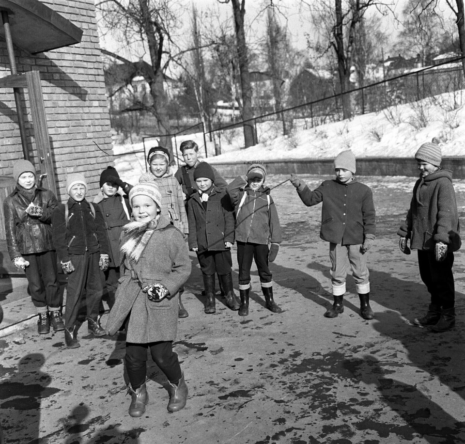 Barn hopper tau på Marienlyst skole, mars 1958. 10 barn på rekke, hvor ta barn holder hoppetauet.
