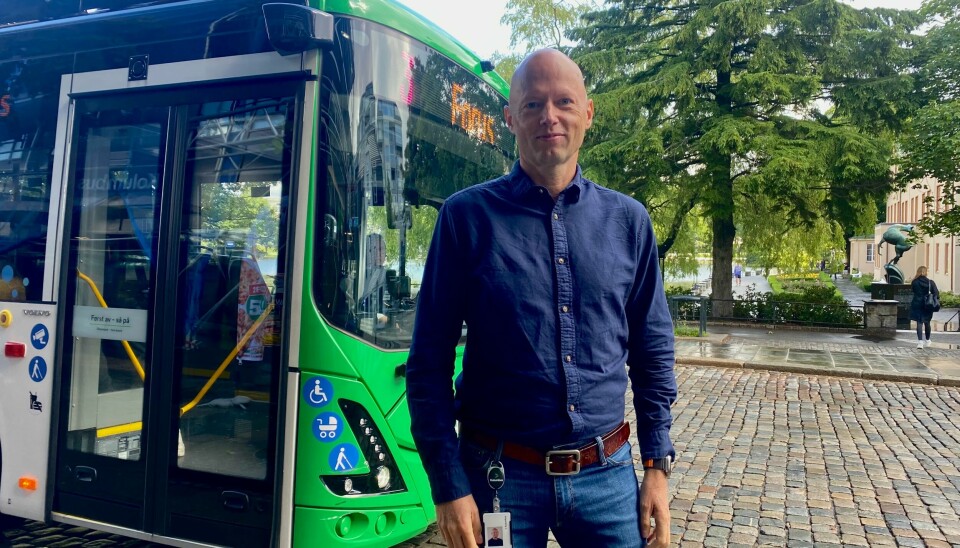 Kjetil Nordbø, kundeserviceleder i Kolumbus. En mann i blå skjorte og jeans foran en buss.