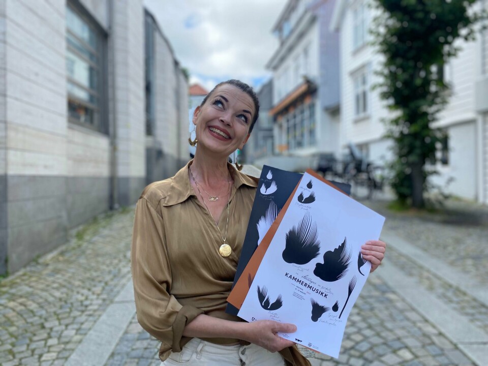 Katrine Lilleland er sjef for Kammermusikkfestivalen. En dame i gullskjorte som holder plakater for Kammermusikkfestivalen.