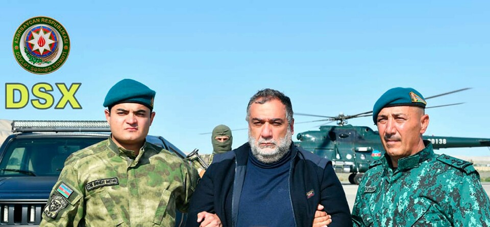 Grensevakten la onsdag ut et bilde som viser Vardanyan holdt fast av to grensevakter ved siden av et helikopter. Det er ikke kjent når og hvor bildet er tatt. Grensevakta la onsdag ut eit bilde som viser Vardanyan halden fast av to grensevakter ved sida av eit helikopter. Det er ikkje kjent når og kor bildet er teke. Foto: Grensevakttenesta til Azerbajdsjan / AP / NTB