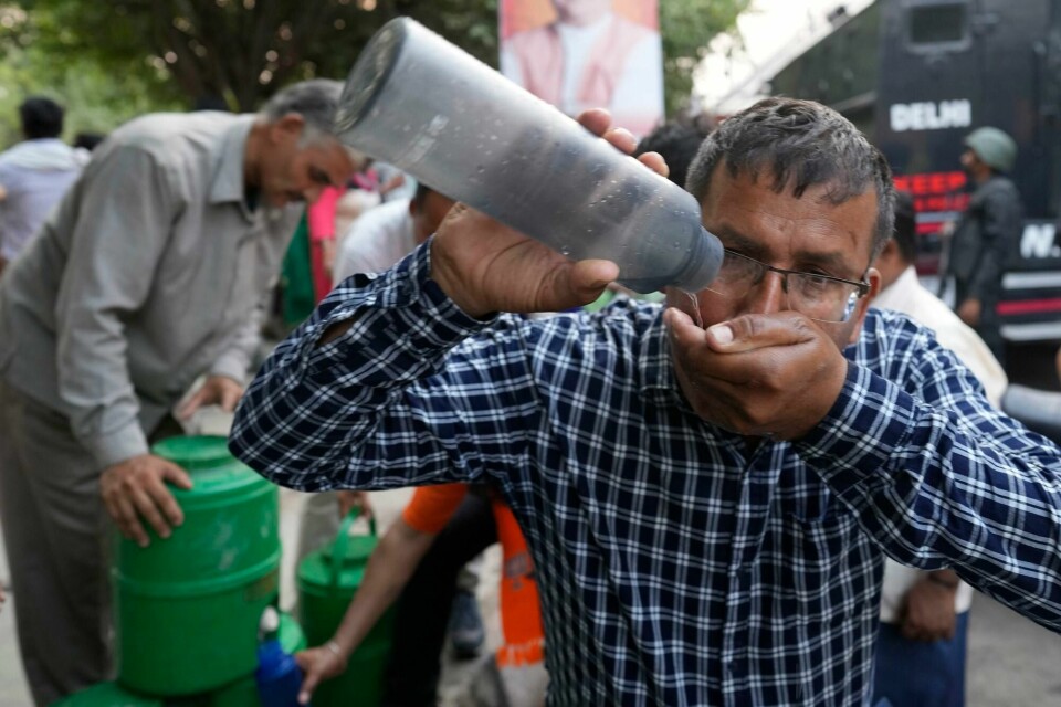 En mann drikker vann fra en vannstasjon som er satt opp i New Delhi i forbindelse med det svært varme været i India. A man drinks water at a roadside stall serving free drinking water to commuters as heat wave continues to grip the Indian capital, New Delhi, India, Wednesday, May 22, 2024. (AP Photo/Manish Swarup)