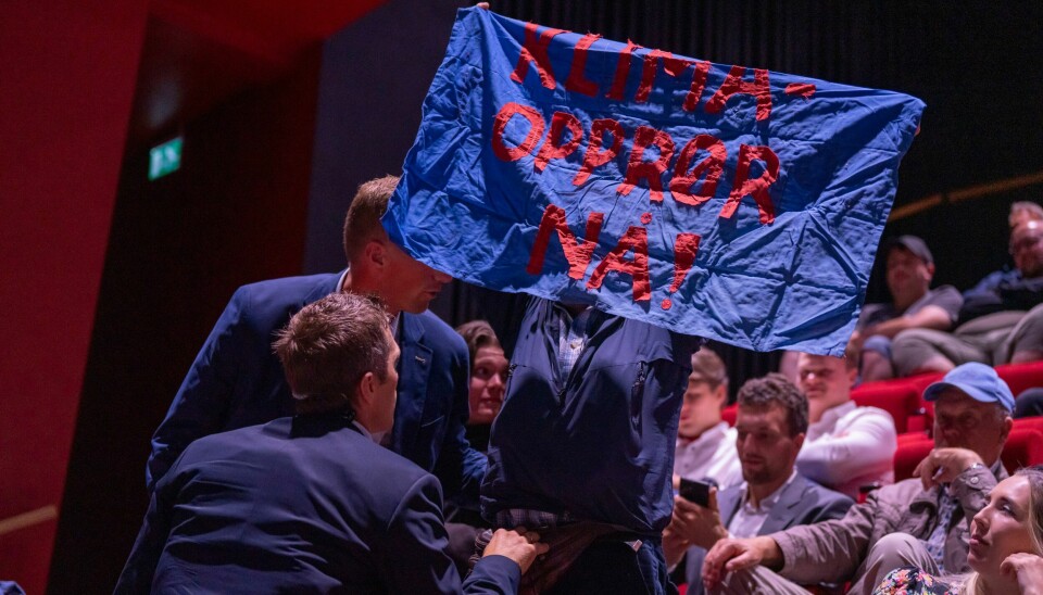 En aktivist holdt opp et banner og ropte ut et klimabudskap under NRKs direktesendte partilederdebatt på kulturhuset i Arendal torsdag kveld. En aktivist blir båret bort fra NRKs direktesendte partilederdebatt på kulturhuset i Arendal torsdag kveld.Foto: Heiko Junge / NTB