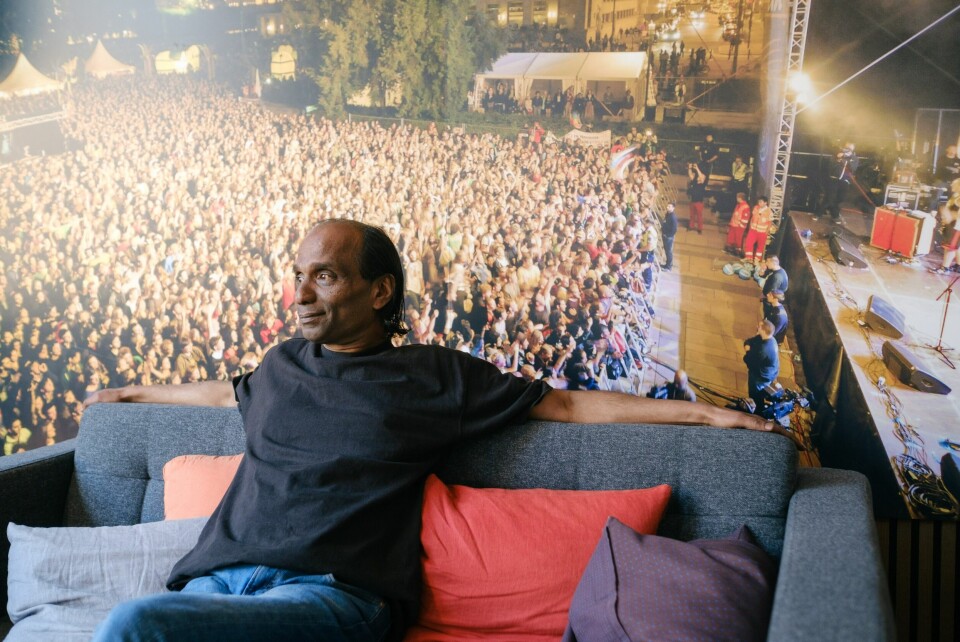Ashley Shiri har vært involvert i Melafestivalen helt siden starten i 2001. Bildet bak ham er fra konserten med Manu Chao i 2012 som samlet titusenvis på Rådhusplassen i Oslo. Festivalsjef i Mela, Ashley Shiri, sitter foran et konsertfotografi på Melahuset i Oslo.