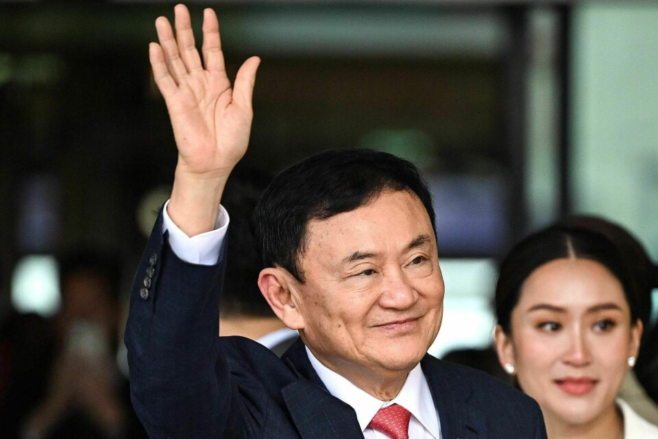 Tidligere statsminister i Thailand, Thaksin Shinawatra, hilser sine tilheneger etter å ha landet på flyplassen i Bangkok etter 15 år i eksil. Til høyre datteren Paetongtarn Shinawatra. Nå må han trolig sone flere år i fengsel. Former Thai Prime Minister Thaksin Shinawatra greets his supporters next to his daughter Paetongtarn Shinawatra (R) after landing at Bangkok's Don Mueang airport on August 22, 2023. Thaksin Shinawatra bowed in homage to the Thai king's portrait as he returned to the kingdom Tuesday after 15 years in exile, before being led away by officials to be processed on multiple outstanding criminal cases. (Photo by Manan VATSYAYANA / AFP)