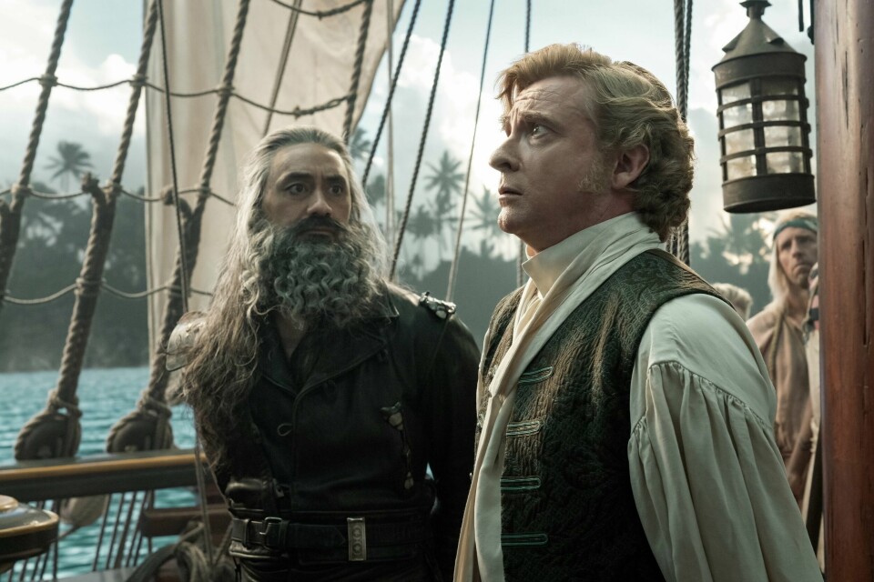 Taika Waititi og Rhys Darby er sjørøvere av høyst forskjellig kaliber i «Our Flag Means Death», to tredeler komedie og resten en overraskende mannlig romanse. Taika Waititi og Rhys Darby er sjørøvere av høyst forskjellig kaliber i «Our Flag Means Death», to tredeler komedie og resten en overraskende mannlig romanse.
