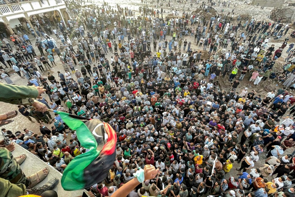 Mandag demonstrerte folk i Derna mot myndighetene, som de mener ikke har tatt ansvar for å forebygge katastrofen. TOPSHOT - People gather for a demonstration outside the surviving Al-Sahaba mosque in Libya's eastern city of Derna on September 18, 2023, as they protest against government neglect to the two dams which broke and led to the deadly flash floods that hit the city the prior week. A week after a tsunami-sized flash flood devastated the Libyan coastal city of Derna, sweeping thousands to their deaths, the international aid effort to help the grieving survivors slowly gathered pace. The enormous flood, fuelled by torrential rains on September 10, had broken through two upstream dams and sent a giant wave crashing down the previously dry river bed, or wadi, that bisects the city of about 100,000 people. (Photo by Hussam AHMED / AFP)