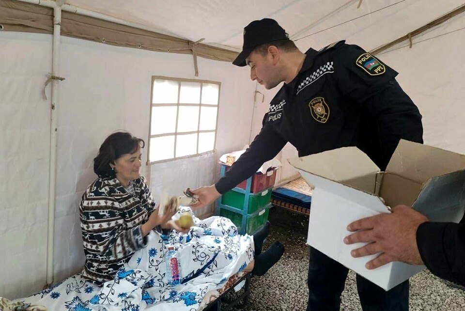 Et bilde gitt ut av aserbajdsjanske myndigheter viser en aserbajdsjansk politimann som gir mat til en etnisk armensk kvinne i en leir i Khojaly i Nagorno-Karabakh. Et bilde gitt ut av aserbajdsjanske myndigheter viser en aserbajdsjansk politimann som gir mat til en etnisk armensk kvinne i en leir i Khojaly i Nagorno-Karabakh. Foto: Aserbajdsjans innenriksdepartement via AP / NTB