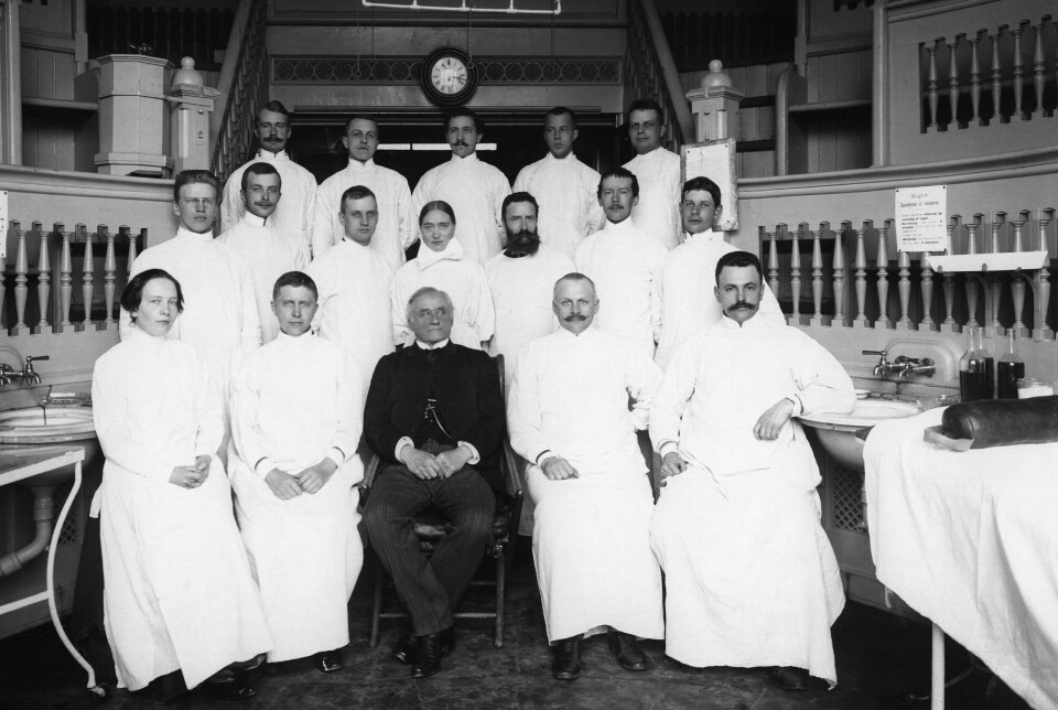 RIKSHOSPITALET 1904: Ulike yrkesgrupper ved kirurgisk avdeling A i Pilestredet 32. De mannlige legene og kvinnen til venstre er nevnt med fullt navn, mens de to i midten er kalt operasjonssøster «Mina» og sykevokter «Nils». RIKSHOSPITALET 1904: Ulike yrkesgrupper ved kirurgisk avdeling A i Pilestredet 32. De mannlige legene og kvinnen til venstre er nevnt med fullt navn, mens de to i midten er kalt operasjonssøster «Mina» og sykevokter «Nils».
