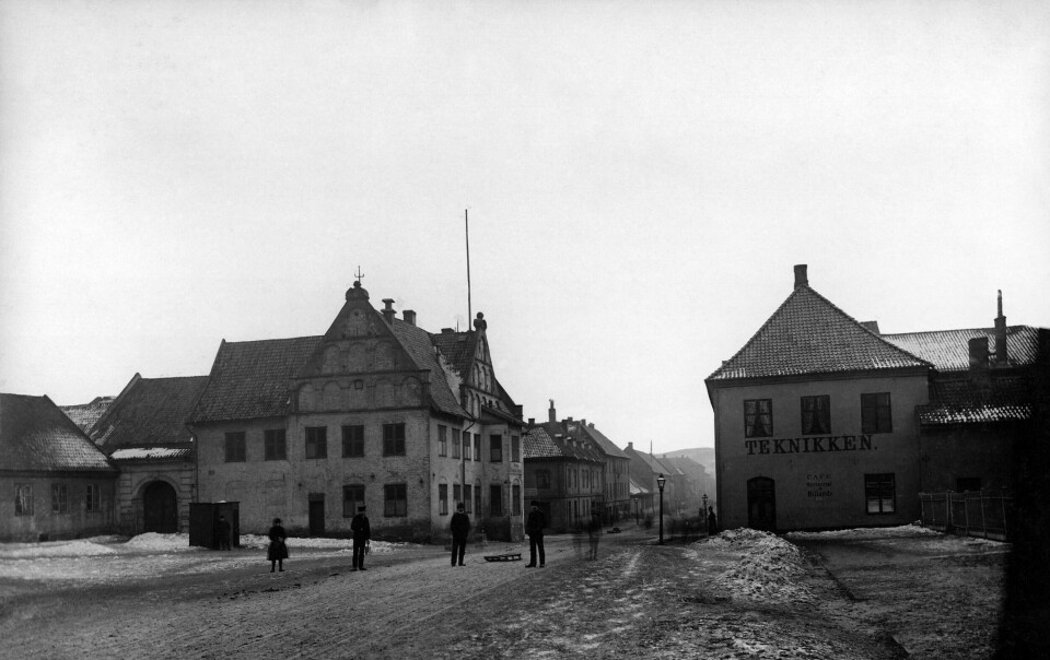 CHRISTIANIA TORV CIRKA 1890–95: Byens eldste bevarte bindingsverkshus, Skarpretteren/Bøddelen/ Mestermannens bolig helt til venstre. Seinere holdt Universitetets Medisinske fakultet til her, derav navnet Anatomigården, og billedhogger Brynjulf Bergslien hadde atelier her til cirka 1900. Nå Galleri BOA. I midten rådmann Lauritz Hansens gård, som sto ferdig to år etter byanleggelsen, fra 1850-tallet Garnisonssykehus, nå kafe Celsius og Oslo Kunstforening. Til høyre byens første rådhus. Firkanten på plassen er antagelig et pissoar. CHRISTIANIA TORV CIRKA 1890–95: Byens eldste bevarte bindingsverkshus, Skarpretteren/Bøddelen/ Mestermannens bolig helt til venstre. Seinere holdt Universitetets Medisinske fakultet til her, derav navnet Anatomigården, og billedhogger Brynjulf Bergslien hadde atelier her til cirka 1900. Nå Galleri BOA. I midten rådmann Lauritz Hansens gård, som sto ferdig to år etter byanleggelsen, fra 1850-tallet Garnisonssykehus, nå kafe Celsius og Oslo Kunstforening. Til høyre byens første rådhus. Firkanten på plassen er antagelig et pissoar.