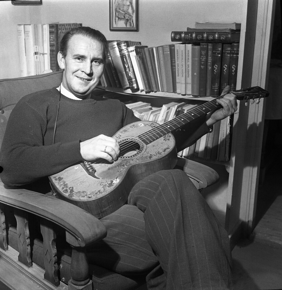 Visesangeren Alf Prøysen i sitt hjem, med gitar.