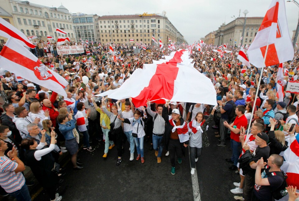 Demonstrasjon i Hviterussland. FILE - In this Aug. 23, 2020, file photo, demonstrators carry an old Belarusian national flag as thousands gather for a protest at Independence Square in Minsk, Belarus. With anti-government protests in Belarus now in their third week including rallies that brought out an estimated 200,000 people in Minsk for the last two Sundays authoritarian President Alexander Lukashenko is moving to squelch the demonstrations gradually with vague promises of reforms mixed with threats, court summonses and the selective jailing of leading activists. (AP Photo/Dmitri Lovetsky, File)