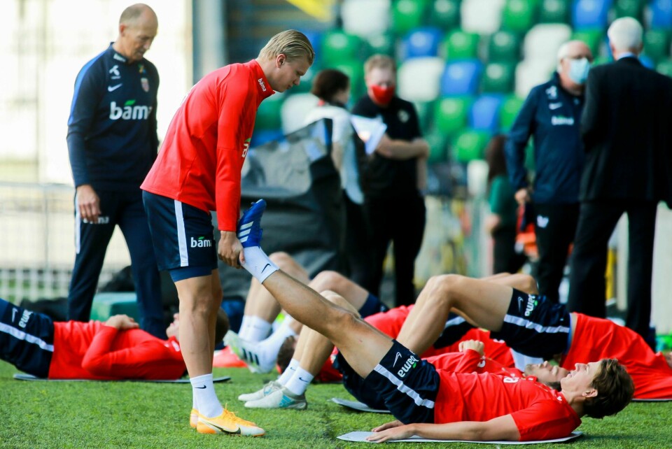 Erling Braut Haaland gir Sander Berge en hjelpende hånd under en trening med landslaget på Windsor Park i Belfast søndag.