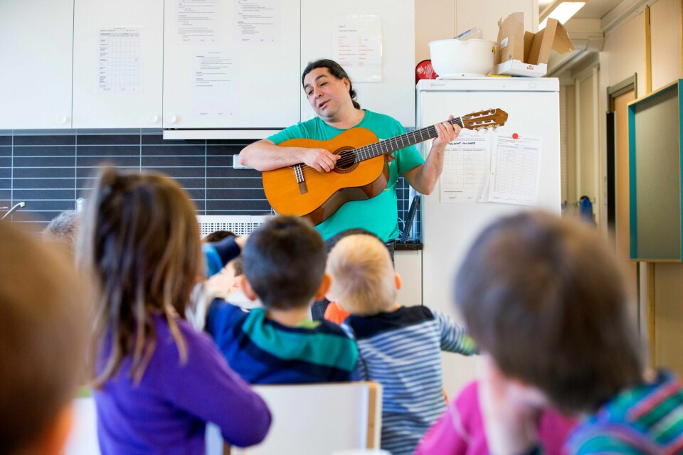 Illustrasjon fra matpause/måltid i barnehage. En mann med gitar spiller for barna.