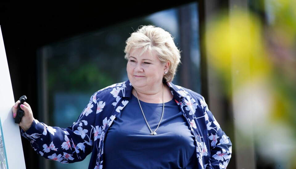 Statsminister Erna Solberg (H) er på valgkampturné før stortingsvalget 2021. Bildet er av statsminister Erna Solberg. Hun smiler mens hun lener sin høyre hånd mot en vegg.