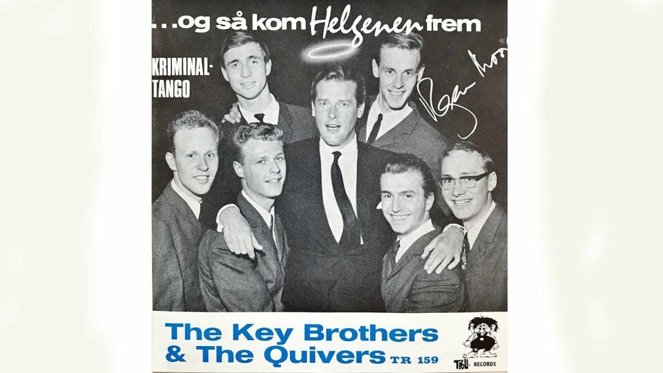 Roger Moore, «The Saint» i egen person, omringet av The Key Brothers og The Quivers, på omslaget av «Og så kom Helgenen frem». Signaturen var trykt på alle eksemplar, men vi likte å tro at den var ekte.