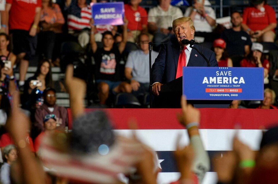 Donald Trump kobler seg selv stadig mer til konspirasjonsbevegelsen QAnon. Her taler han under et møte i Ohio i september samtidig som QAnon-tilhengere holder en symbolsk pekefinger i været. En gest som skal minne om QAnon-mottoet «Where We Go One We Go All». Under avslutningen av møtet ble det spilt en sang som minnet veldig om bevegelsens «hymne». (FILES) In this file photo taken on September 17, 2022 audience members put their index finger up to symbolize America First while President Donald Trump speaks at a Save America Rally to support Republican candidates running for state and federal offices in the state of Ohio at the Covelli Centre in Youngstown, Ohio. - Ensnared in legal probes as he mulls a second White House run in 2024, Donald Trump is injecting new life into the fading QAnon conspiracy cult -- whose members have embraced him as a new icon. (Photo by JEFF SWENSEN / GETTY IMAGES NORTH AMERICA / AFP)