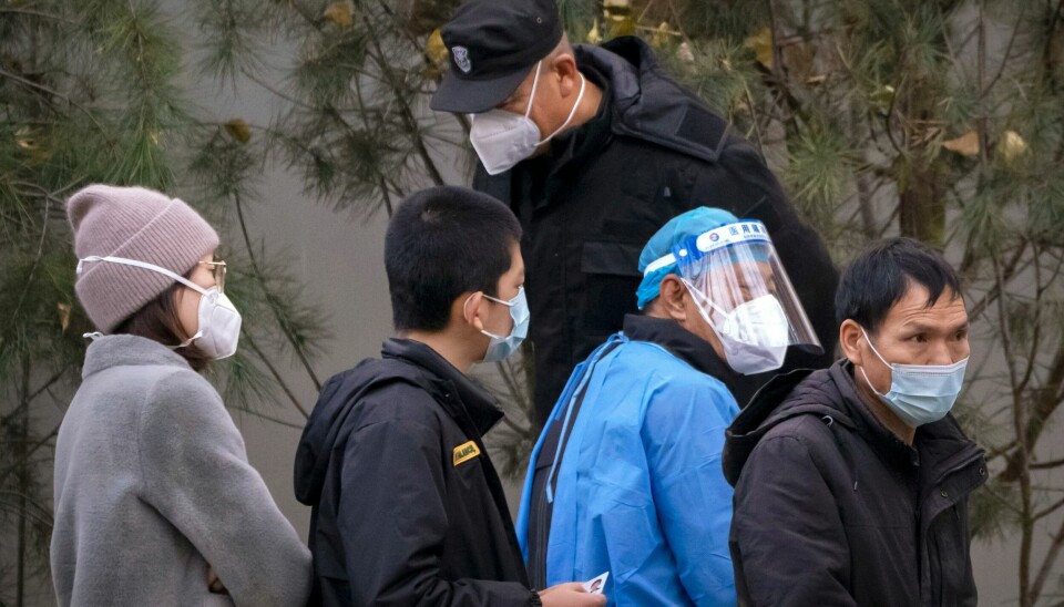 En vakt snakker med mennesker som står i kø for å bli koronatestet i Beijing. En vakt snakker med mennesker som står i kø for å bli koronatestet i Beijing. Foto: Mark Schiefelbein / AP / NTB