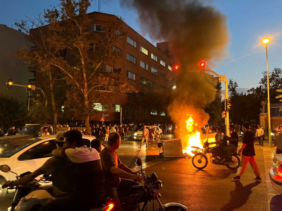 Demonstrasjoner i Teheran etter at 22-årige Mahsa Amini døde i politiets varetekt. In this Monday, Sept. 19, 2022, photo taken by an individual not employed by the Associated Press and obtained by the AP outside Iran, a police motorcycle and a trash bin are burning during a protest over the death of Mahsa Amini, a 22-year-old woman who had been detained by the nation's morality police, in downtown Tehran, Iran. Spontaneous mass gatherings to persistent scattered demonstrations have unfolded elsewhere in Iran, as nationwide protests over the death of a young woman in the custody of the morality police enter their fourth week.(AP Photo)