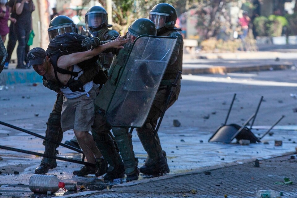 TOPSHOT - Riot police detain a demonstrator during clashes in Santiago on October 24, 2019 after a week of street violence which erupted against a now suspended metro fare hike but spiralled into general discontent. - A general strike in Chile went into its second day following a week of street protests for general discontent at low salaries and pensions, high costs of health care and education, and a yawning gap between rich and poor, that left 18 dead. (Photo by Claudio REYES / AFP) TOPSHOT - Riot police detain a demonstrator during clashes in Santiago on October 24, 2019 after a week of street violence which erupted against a now suspended metro fare hike but spiralled into general discontent. - A general strike in Chile went into its second day following a week of street protests for general discontent at low salaries and pensions, high costs of health care and education, and a yawning gap between rich and poor, that left 18 dead. (Photo by Claudio REYES / AFP)